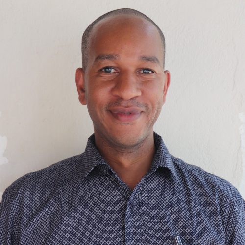 A smiling Tanzanian man with a blue shirt.