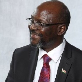 A Tanzanian man with glasses smiling.